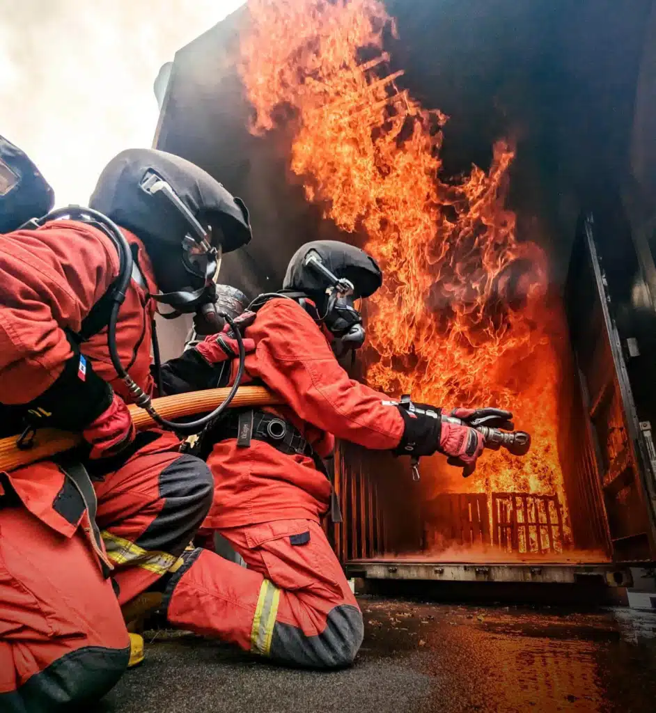 Formation incendie : stagiaires en tenue d’intervention attaquant un feu réel à la lance